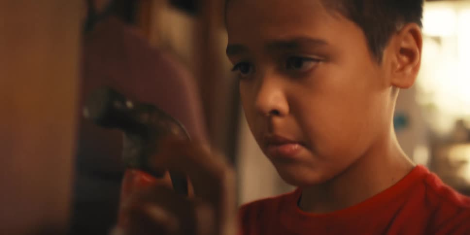 A father watches his son use a hammer