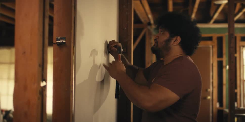 Man holding a nail and hammer with an irritated facial expression
