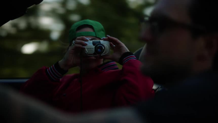 Woman riding in a convertible taking selfies and pictures with a camera