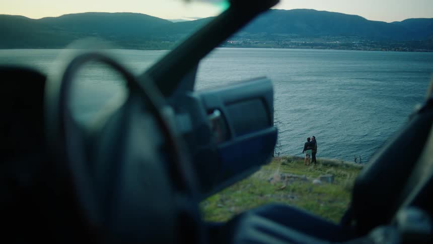 View from inside a car and a couple walking and kissing hand in hand by the lake