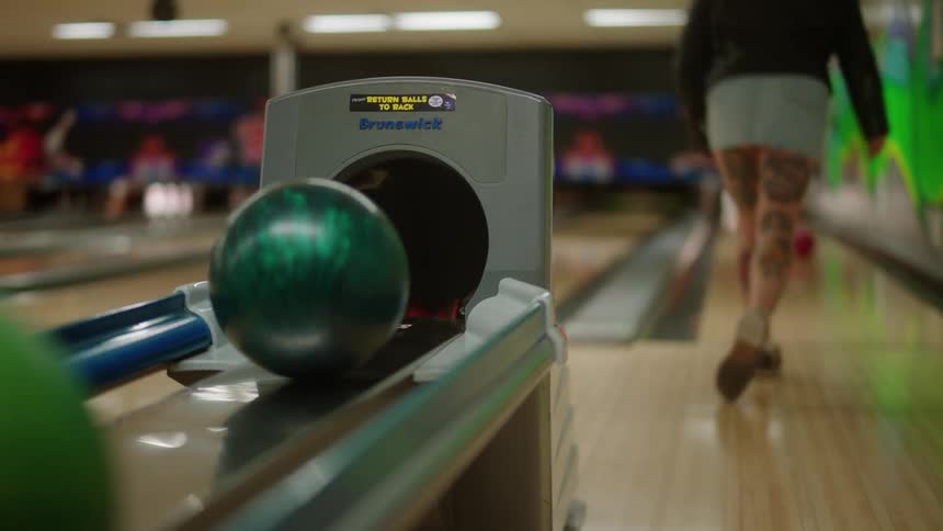 Woman throwing a red ball in a bowling game