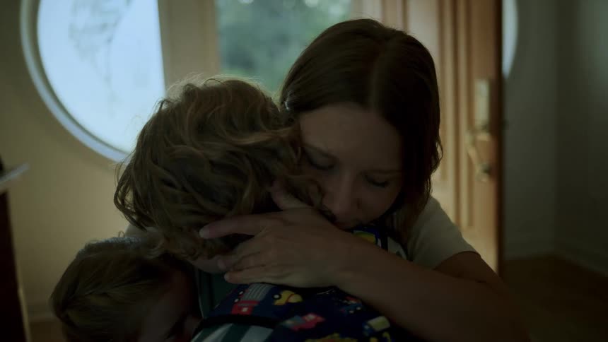 Mother hugging her two young children indoors