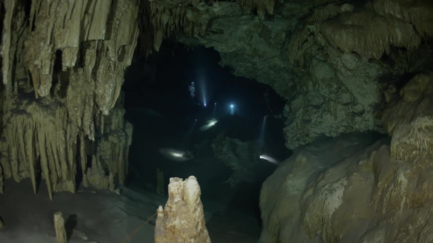 Scuba divers travel in the dark cave