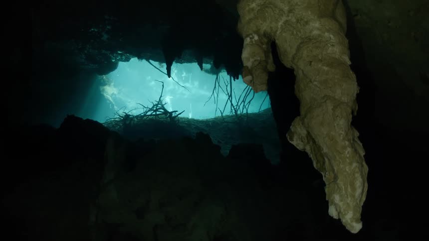 Light shines into an underwater cavern through the mouth of the cave