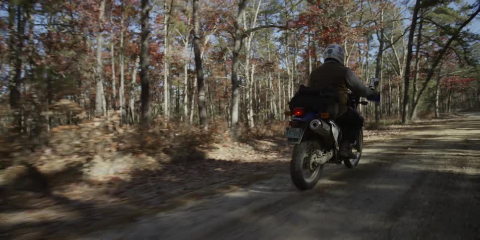 A motorcycle drives down a dirt road