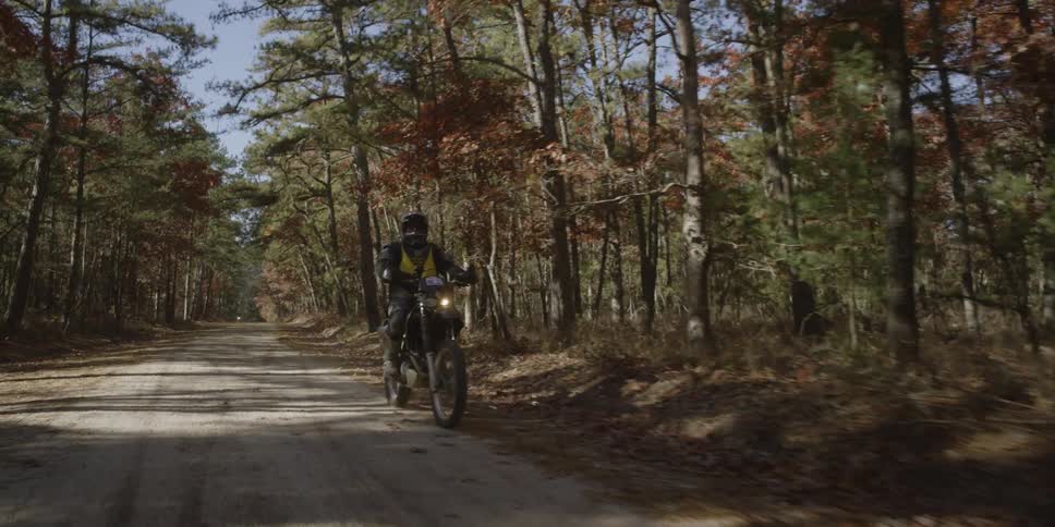 Person riding dirt bike on a path through the woods