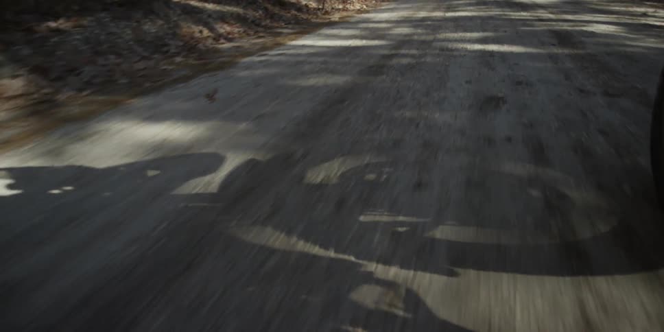 The shadow of a motorcycle wheel moves along a dirt road
