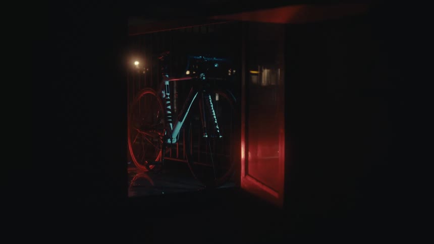Sports bike leaning against a fence and a train passing in the background at night