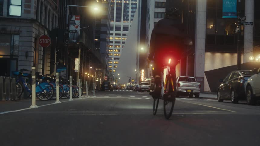 Person cycling on the street of an illuminated metropolis