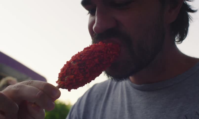 A man eats fried cheese outdoors
