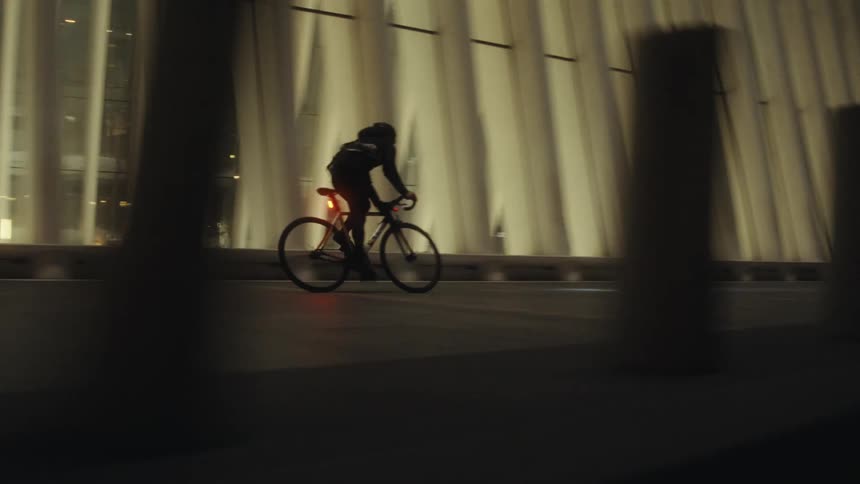 Man rides a bicycle across a modern bridge leading to a metropolis