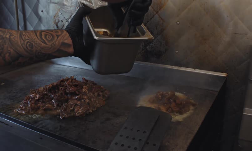 Dropping meats of meat on a hot metal plate to cook them