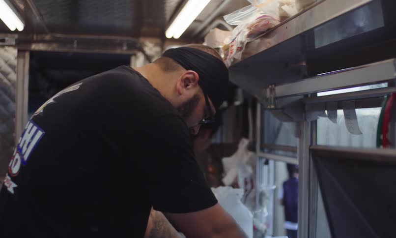 Three men inside a mobile kitchen preparing food