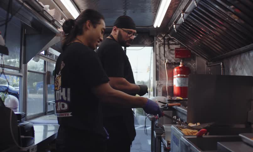 Two men cooking in a mobile kitchen