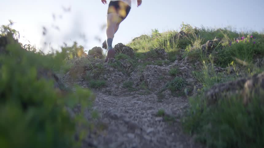 Runner runs up an uneven slope on a sunny summer day