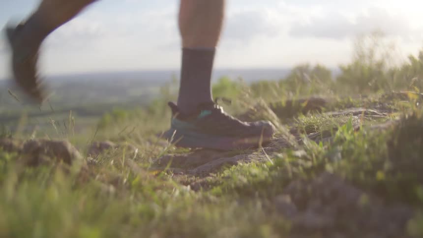 A white person runs over rocks on top of a hill