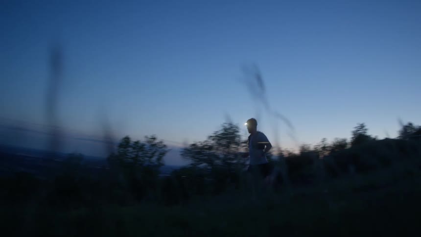 A man jogging through a field at night with a lantern attached to his head