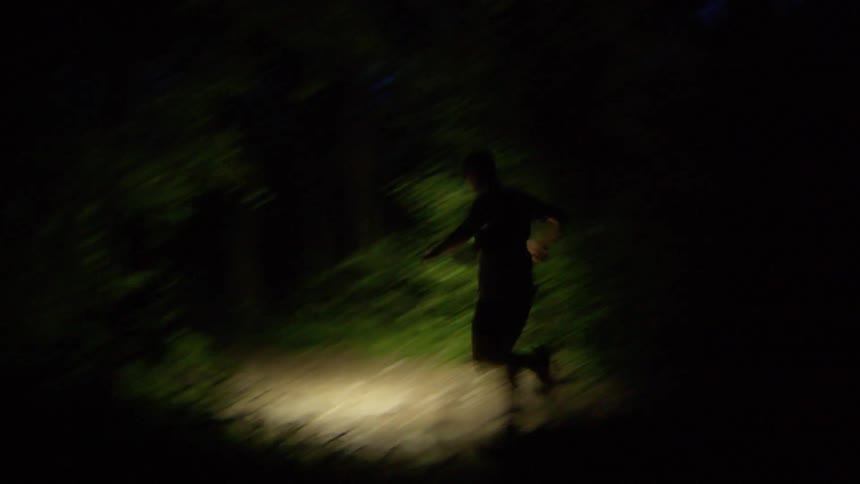 A man runs through the forest at night