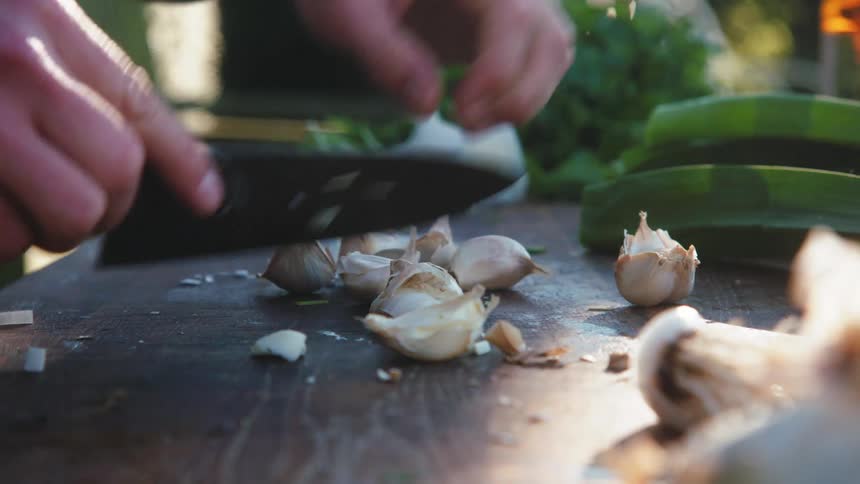Chef cutting and smashing garlic cloves with a knife