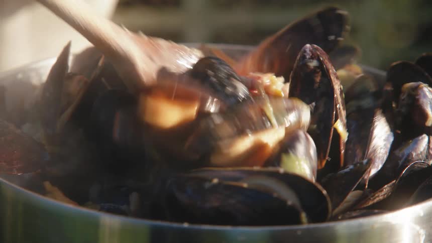 Closeup of a metal pot containing steaming clams