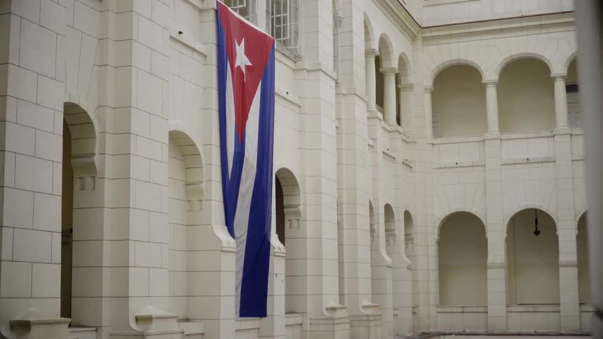 The flag of cuba hangs from a building