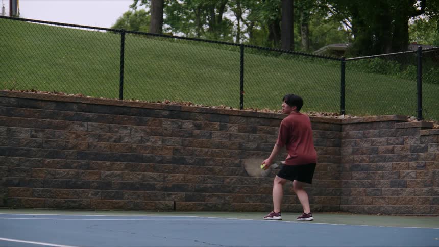 Boy throwing a green tennis ball on the court