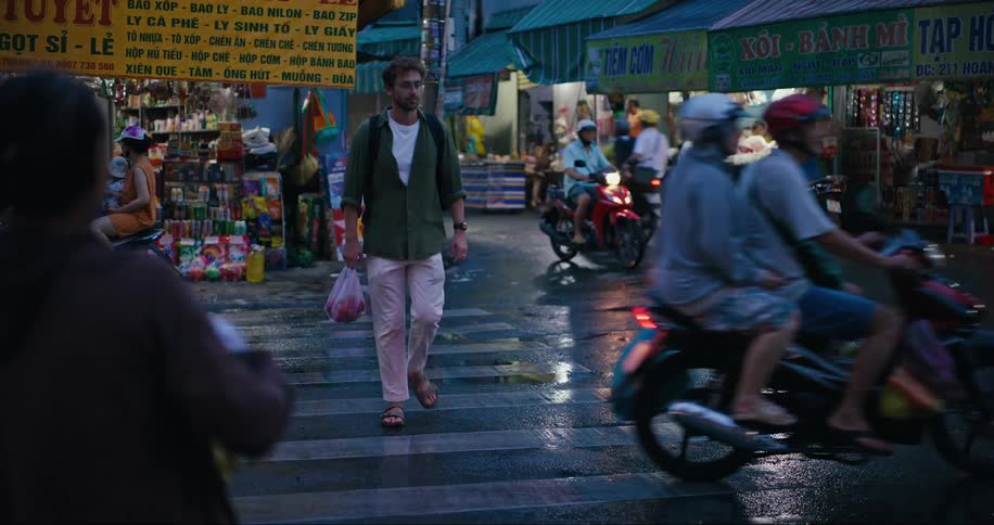 A white male walks through a bustling intersection in an asian country