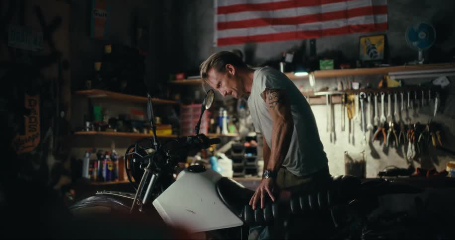 Mechanic attaching a black seat to a motorcycle inside a workshop
