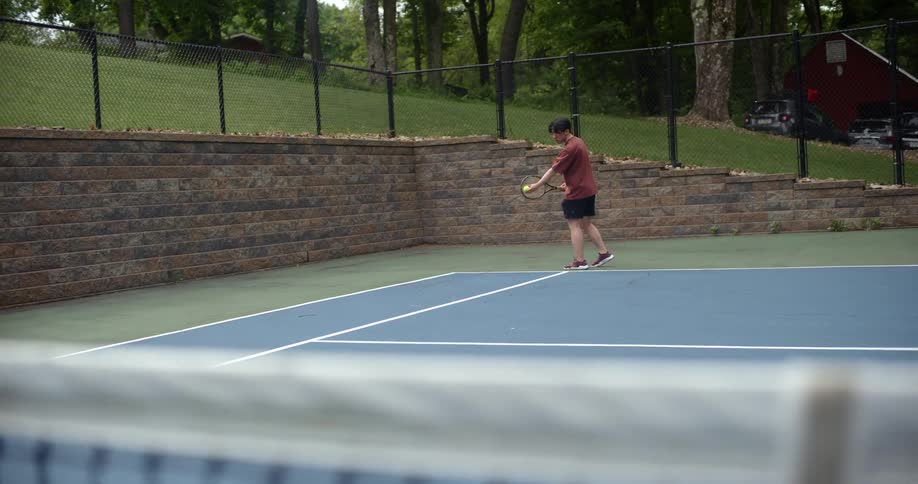 A man serves the tennis ball
