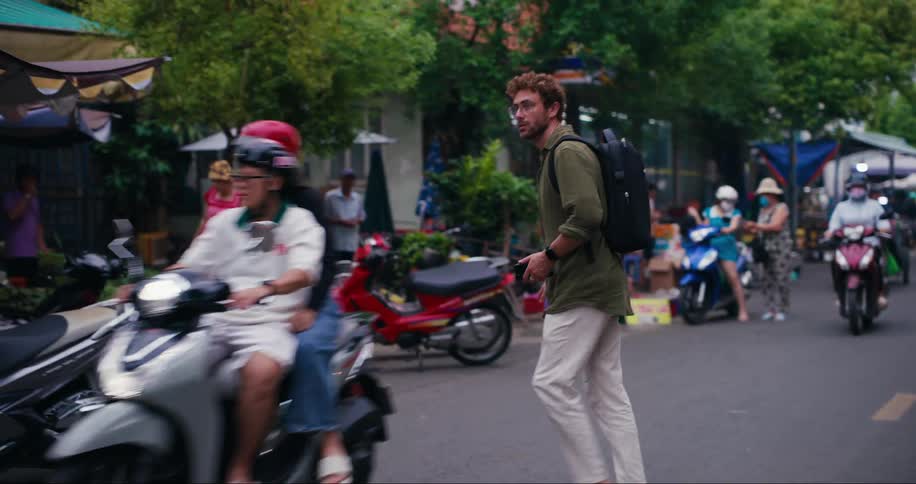 Man crossing the street while traveling through a city on a busy street with street markets around