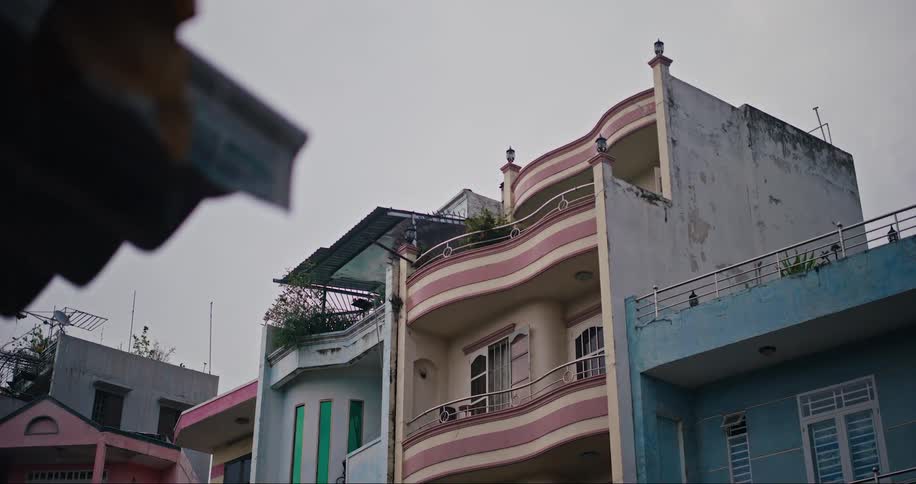 Two adjacent buildings with balconies one blue and one pink as it rains