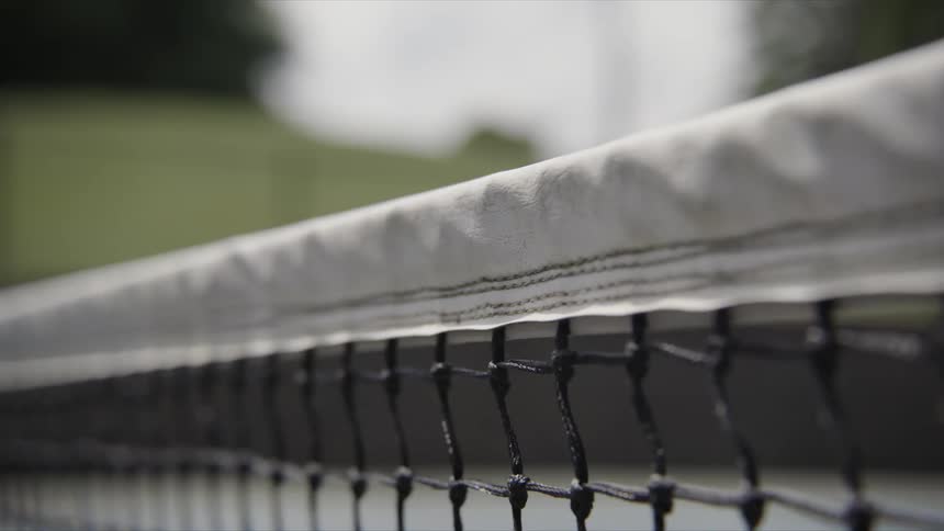 Close up of a tennis ball hitting white top edge of the tennis net