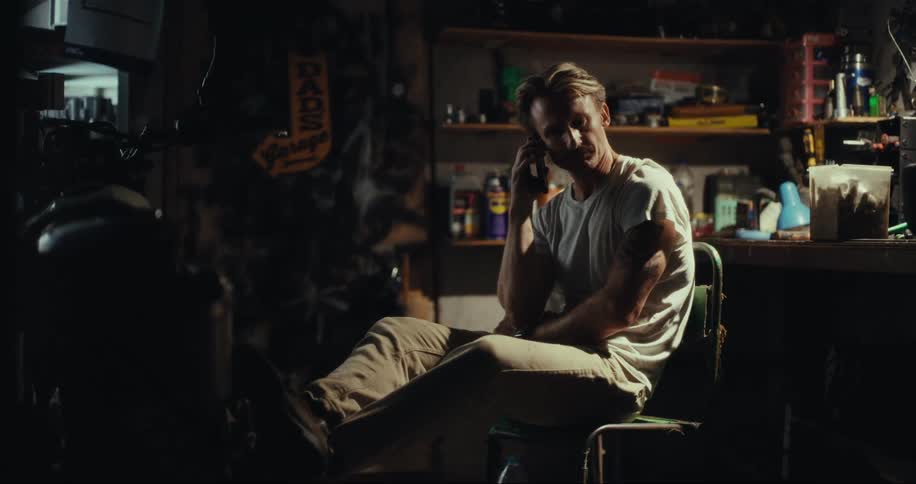 Man sitting inside a workshop talking on his cell phone