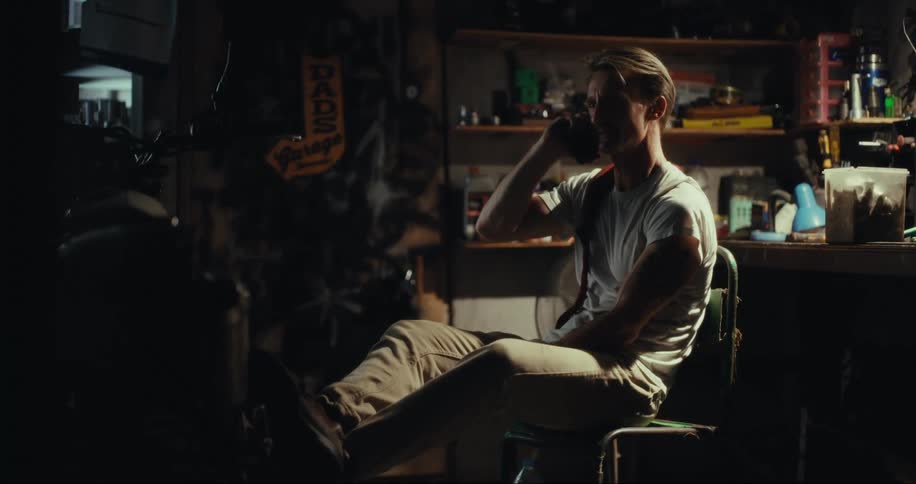 A man sitting in a dark workshop talking on the phone