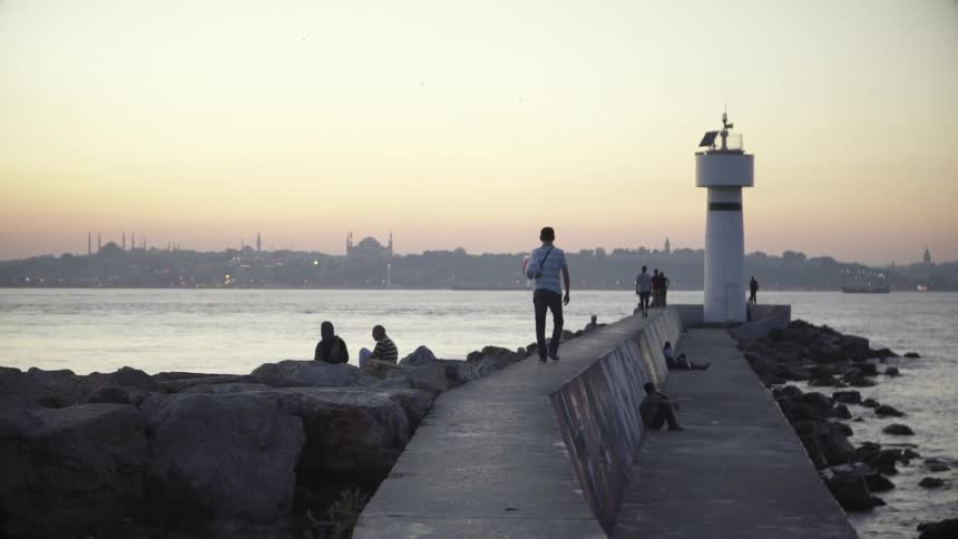 A man walks on a stone walkway toward a building