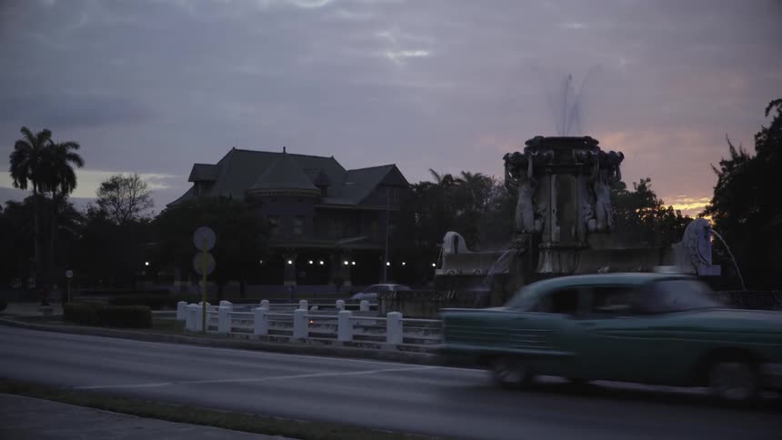 A busy road with old cars and a fountain