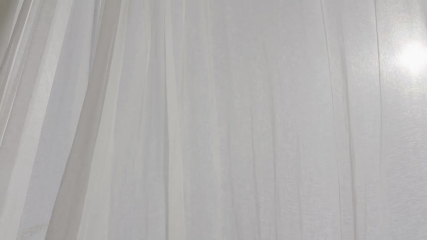 White curtain in motion with a sun in the background