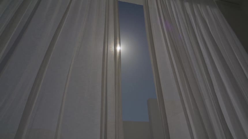 Curtain on the inside of a door with a view of the sun in a blue sky