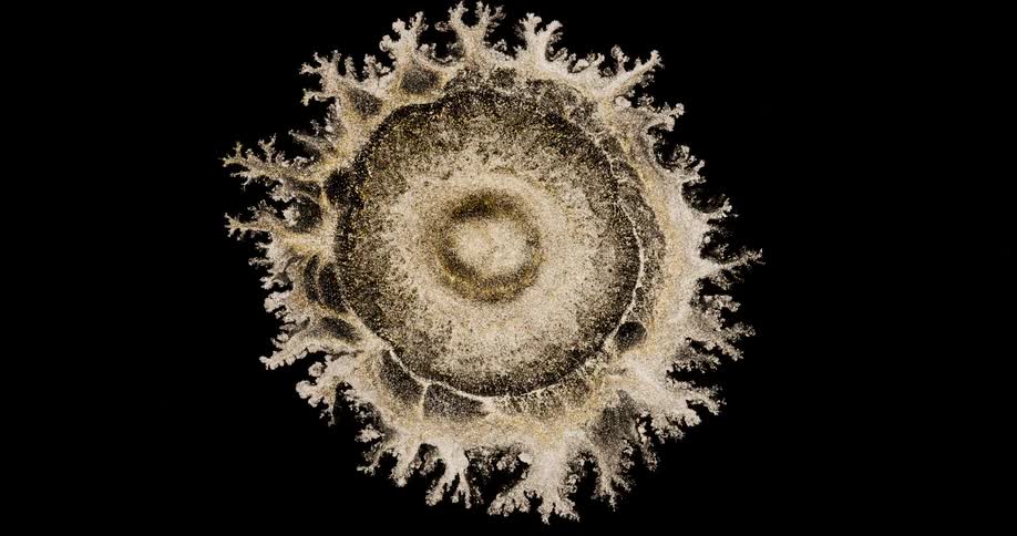 An expanding blob of glittering dust branching out over a dark background