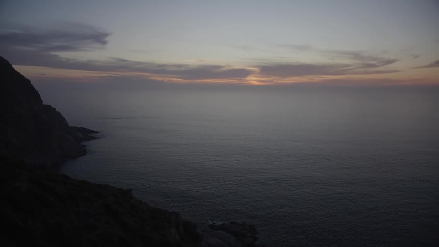 Landscape of rocky coastline by the sea with reddish dawn sky