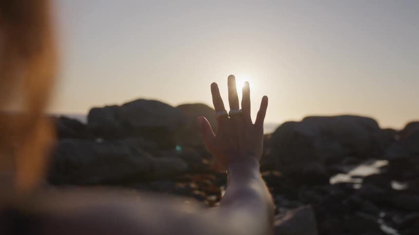Womans hand in a natural setting against the morning sun