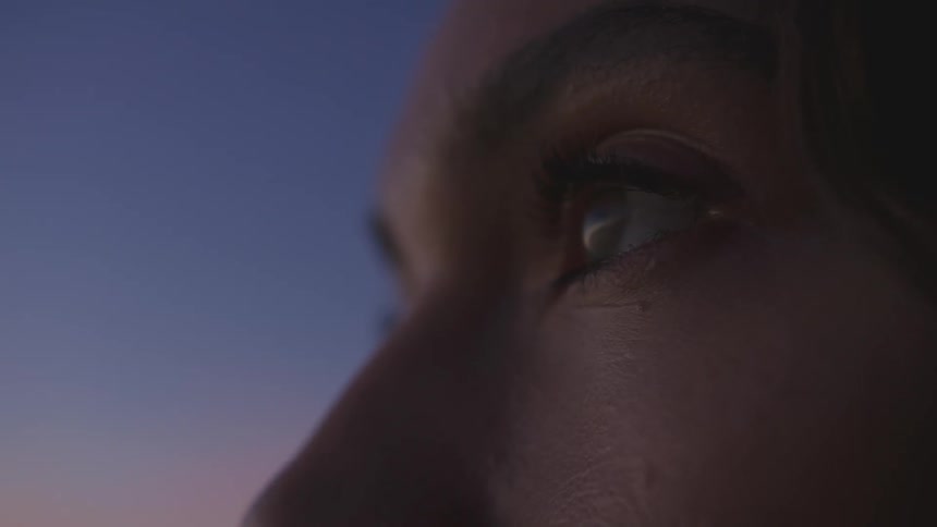 Woman outdoors views the landscape after sunset while a red afterglow tints the horizon