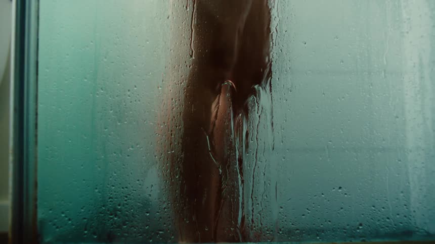 Legs of a person inside a glass shower box taking a shower