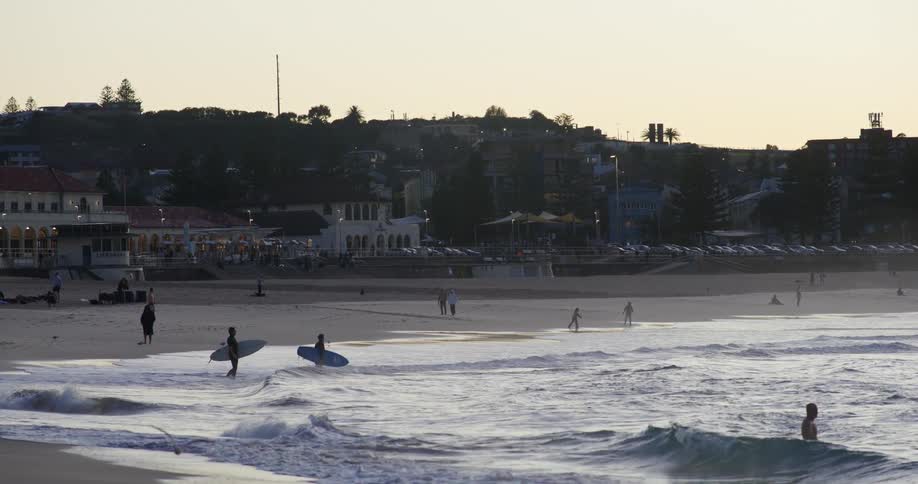 Surfers and bathers on a beach in the late afternoon