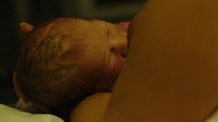 Newborn baby sucking on mothers breast