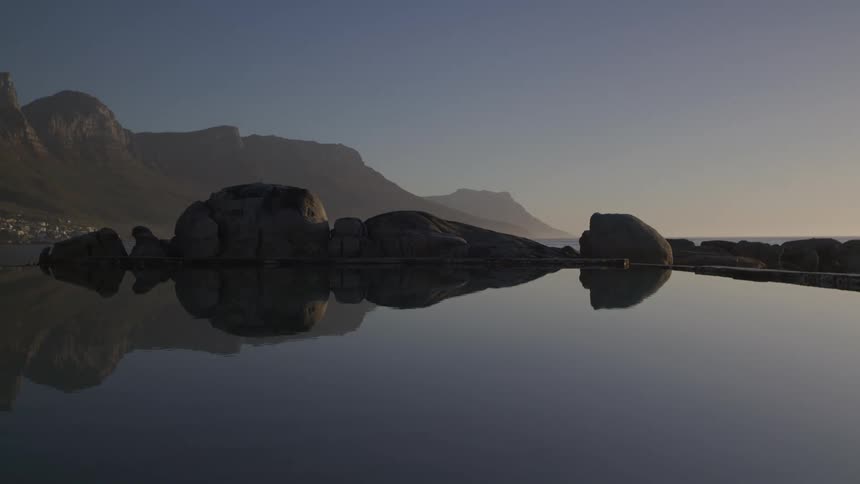 Natural landscape of a calm lake surrounded by stones and rocks in the morning