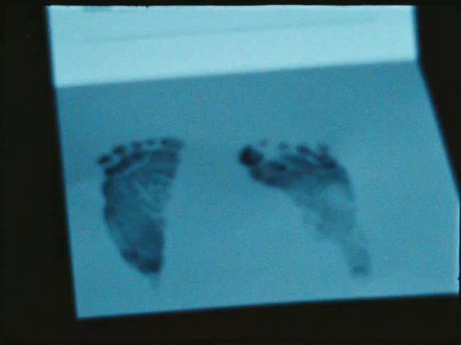 Tiny baby feet are imprinted on a card captured in vintage film
