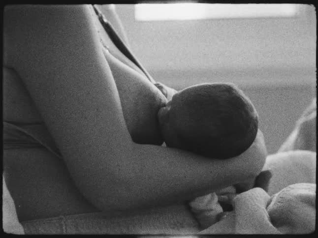 A black and white image of a mother breastfeeding her newborn
