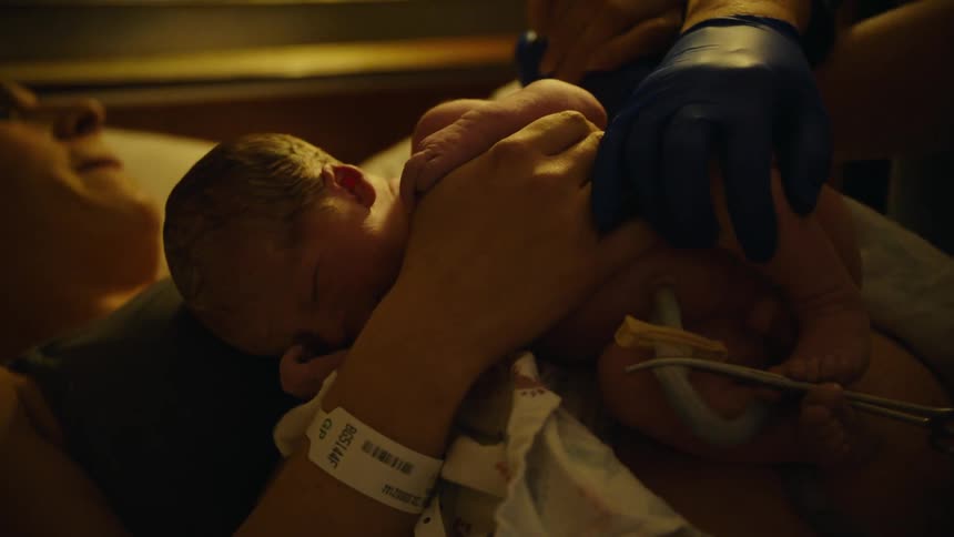 Mother lying with her newborn baby on her chest and the baby with the umbilical cord and hands with doctors moons nearby