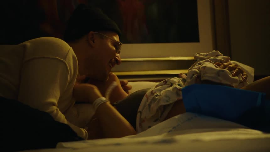 A new father lovingly gazes at his newborn in a dimly lit room